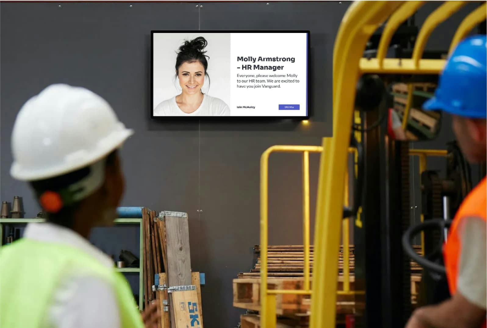 Factory workers looking at industrial digital signage in a warehouse