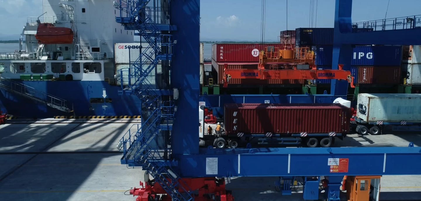 Cargo containers being loaded onto a ship at a bustling port.